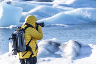 A photographer photographing the floating icebergs in the Jokulsarlon glacier lagoon in Iceland.