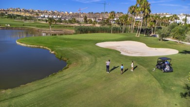 Aerial drone wide view of three people playing in a luxury golf course in summer