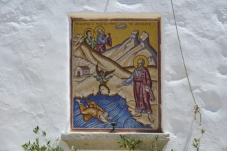 Mosaic depiction on a white wall showing a religious scene with several figures and mountains,