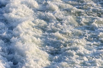 Agitated white foaming water, spray on cascades at the Lech weir, river Lech, background, Landsberg