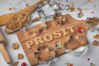 Cheers lettering made from biscuit dough on a wooden board, baking accessories, cookie cutters