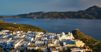 View of Plaka village on Milos island with traditional greek white houses on sunset. Plaka town,