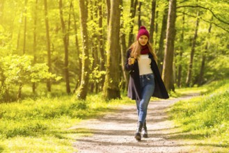 Latin girl with a black jacket, scarf and red woolen hat enjoying in an autumn park, walking along