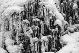 Icicles on the rock face at Skogafoss waterfall, black and white photo, Sudurland, Iceland, Europe
