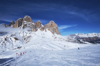 View of a ski resort piste with people skiing in Dolomites in Italy