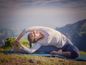 Yoga outdoors, young sporty fit woman doing Hatha Yoga asana parivritta janu sirsasana, Revolved
