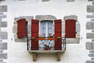 Typical window with balcony, red shutters and potted plants, detail of the façade, Espelette,