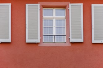 House façade set in red with row of windows and shutters in the old town of Freiburg im Breisgau,