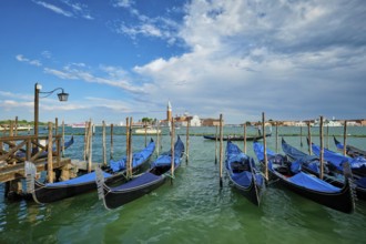 VENICE, ITALY, JUNE 27, 2018: Gondolas and gondolier in lagoon of Venice by Saint Mark (San Marco)