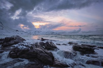 Waves of Norwegian sea on rocky coast in fjord on sunset. Skagsanden beach, Lofoten islands,