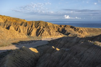 Canyon runs through a landscape of eroded hills at sunrise, Badlands, Issyk Kul Lake in the