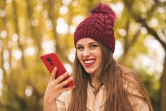 Portrait of a beautiful woman in autumn next to a forest in nature smiling sending a voice note