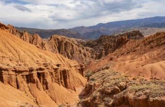 Eroded mountain landscape with sandstone cliffs, canyon with red and orange rock formations,