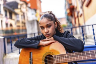 Portrait of a beauty african american woman leaning on an acoustic guitar outside a colorful