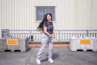 Happy asian young woman dancing k-pop alone in the city