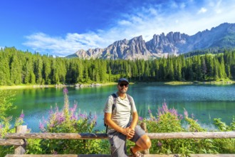 Hiker enjoying the breathtaking view of the emerald waters of lake carezza and the latemar massif