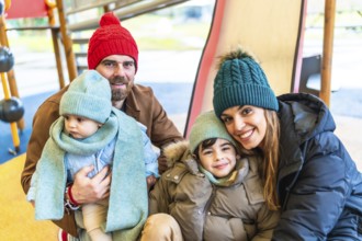 Happy family bundled in winter clothing, smiling and embracing joyfully while enjoying playful