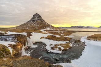Sunrise on the famous Kirkjufell mountain next to the waterfall in winter in Iceland