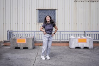 Female asian young K-pop dancer jumping hand on hip performing a choreography in an urban