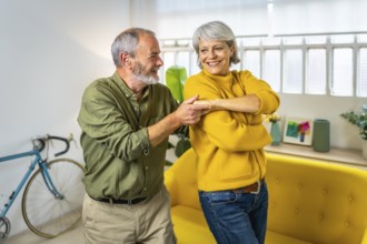 Three quarter length photo of a caucasian senior couple having fun dancing together at home