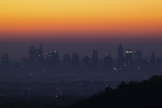 Shortly in front of sunrise, the sky behind the Frankfurt banking skyline turns yellow and orange,