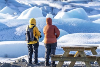 A couple looking at floating icebergs in the Jokulsarlon glacier lagoon in Iceland