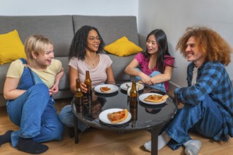 Four young friends sitting around a table, drinking beer and eating pizza, enjoying time together