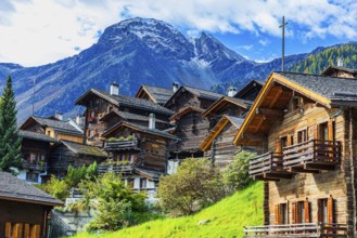 Old wooden houses in the historic village centre, behind the summit of the Scex Marenda mountain,