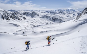 Two ski tourers in mountain landscape with snow, mountain panorama with summit of the Grisons Alps,