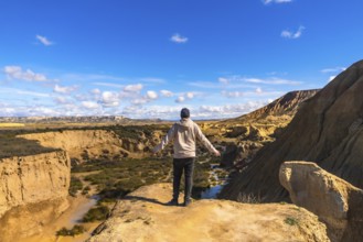 Tourist standing on a cliff with open arms, contemplating the breathtaking view of bardenas reales
