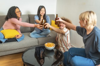 Group of young multi ethnic people having fun and toasting with beer bottles while sitting on a
