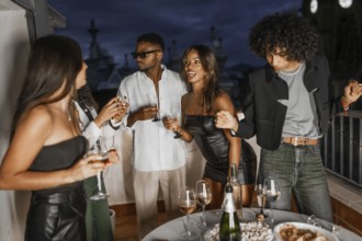 Chic multi-ethnic friends having fun partying in a rooftop at night