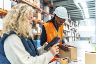 Multiracial female and male manual workers preparing boxes to deliver in a modern warehouse