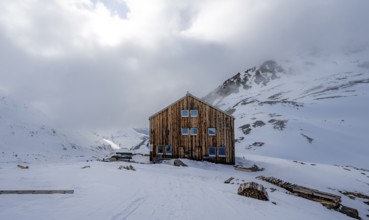 Chamanna Es-cha mountain hut in a wintry, cloudy mountain landscape, Bündner Haute Route ski tour,