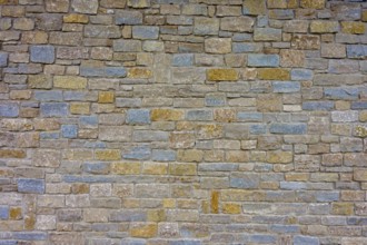 Wall made of different coloured natural stones with a subtle texture and robust appearance,