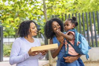 Cute african girl with her mother and grandmother in the park after school day