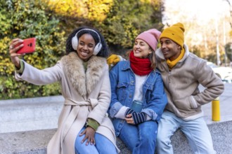 Three friends are taking a selfie in the city during winter, enjoying their time together