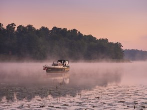 Morning atmosphere at Lake Grienerick, boat anchored, morning mist on the water, Rheinsberg,