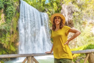 Portrait of a female tourist with a hat looking at La Caprichosa waterfall in the Monasterio de