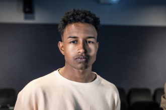 Portrait of a young man standing in a movie theater during a movie session, possibly participating
