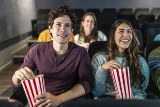 Happy couple enjoying a movie night at the cinema, sharing popcorn and smiles while immersed in the