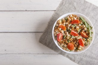 Vegetarian salad of boiled chickpeas, cheese, arugula, mustard and cherry tomatoes on white wooden