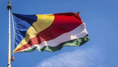 The flag of Seychelles, fluttering in the wind, isolated against a blue sky