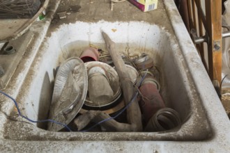 Unwashed dishes and other objects in dirty white sink inside an old barn, Quebec, Canada, North