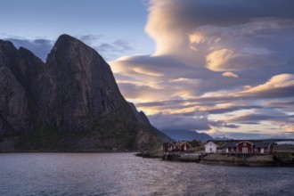 Cloudy landscape, view of Toppoya (Toppoy), the sea and Festhaeltinden mountain. Typical red wooden