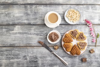 Homemade waffle with chocolate butter and cup of coffee on a gray wooden background. top view, flat