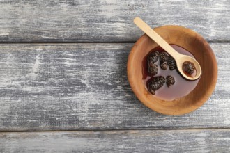 Pine cone jam in wooden bowl on gray wooden background. Top view, flat lay, copy space
