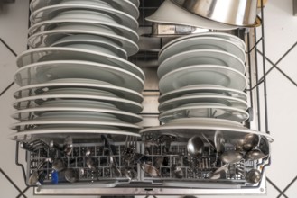 Dishwasher, full, with cleaned crockery, cutlery, cooking utensils