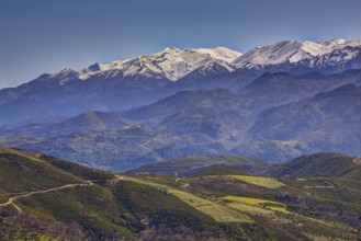 Mountain landscape with snow-covered peaks, green hills and windy paths, Lefka Ori, White