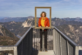 A hiker stands on the 5fingers viewpoint and looks through the picture frame. View from the